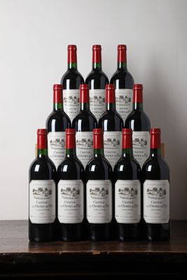 Des bouteilles de vin rouge sont posées sur une table devant un mur blanc.