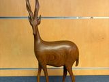 a wooden sculpture of a antelope standing on a pedestal