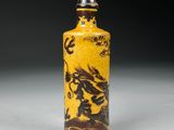 yellow and black glass snuff bottle with a dragon on it