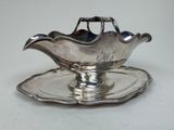 an antique silver plate with a saucer and a spoon on it
