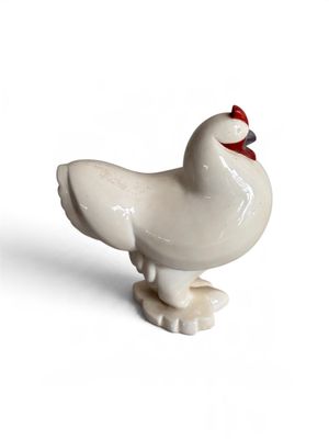 un petit oiseau blanc au bec rouge, posé sur une surface blanche