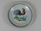 a plate with a rooster painted on it on a table