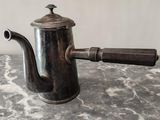 une cafetière en argent avec une poignée en bois, posée sur une table en marbre