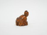 une petite figurine en bois représentant une femme agenouillée par terre