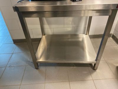 une table en acier inoxydable sur laquelle est posé un micro-ondes