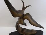 sculpture en bronze représentant un oiseau sur un socle noir, sur fond blanc
