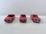 trois petites voitures rouges posées sur une table blanche