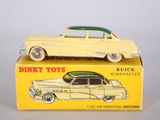 une petite voiture posée sur une boîte, sur une surface blanche