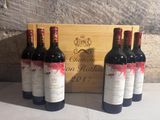three bottles of red wine sit in front of a wooden box