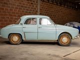 an old car parked in a garage with a tent in the background