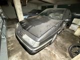 a dirty car parked in a garage next to other cars