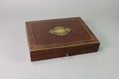 an old wooden box sitting on a white surface with a gold emblem on the lid