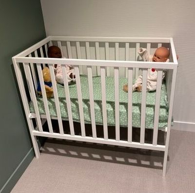 a baby in a crib next to a stuffed animal