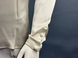 an image of a mannequin wearing a white shirt with buttons on the sleeves