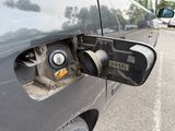 a close up of a car ' s fuel pump with a car in the background