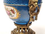 a blue vase with a gold handle on a stand