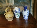 trois vases posés sur une table, avec un tableau en arrière-plan
