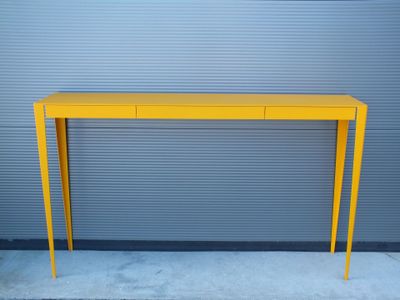 une photo d'une console jaune placée contre un mur