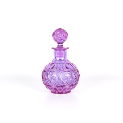 flacon de parfum en verre violet orné d'un motif décoratif sur le bouchon