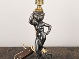 une statue représentant une femme tenant une lampe posée sur une table