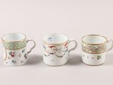three cups with different designs are lined up on a white surface
