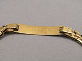 gros plan d'un bracelet en or sur une surface grise