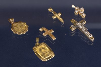 plusieurs pendentifs en forme de croix, en or et en argent, sur un fond noir