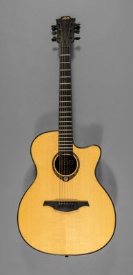 une petite guitare acoustique posée sur un support, devant un fond gris
