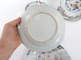 a person holding a white plate with a gold rim
