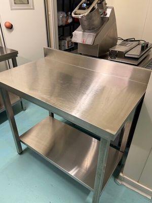 une table en acier inoxydable dans une cuisine, sur laquelle est posé un mixeur