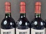 three bottles of red wine are lined up on a table