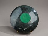 a black and green plate with a green dot on it