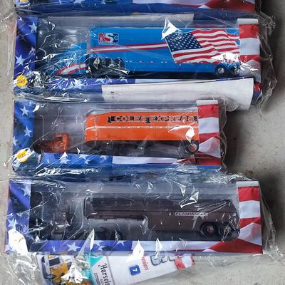 cinq camions miniatures dans des sacs en plastique posés par terre