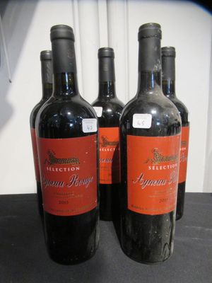 trois bouteilles de vin rouge posées sur une table l'une à côté de l'autre