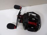 a close up of a black and red fishing reel on a white surface