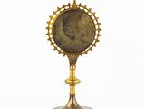 an image of a golden clock on a stand with a cross on top