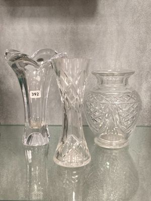 trois vases en verre posés sur une étagère en verre à côté d'une horloge
