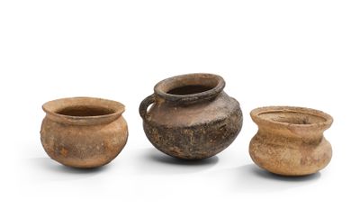 trois pots en argile sont posés les uns à côté des autres sur une surface blanche