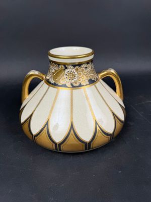 un vase doré et blanc posé sur une surface noire