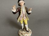 an antique figurine of a man in a brown coat and yellow pants