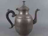 an old silver teapot with a bird on top of it