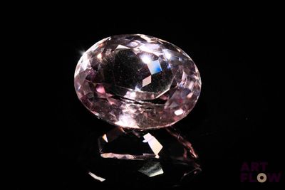 pink diamond on a black surface with a black background