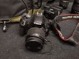 a camera, a camera case, a camera lens, and a camera strap on the floor