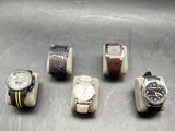several watches are lined up in a row on a metal surface