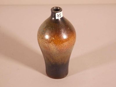 a brown and black vase sitting on a white surface