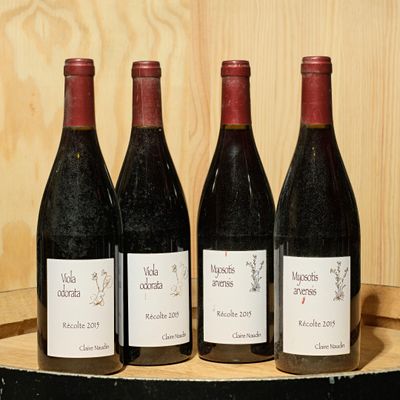 four bottles of wine are lined up on a wooden barrel