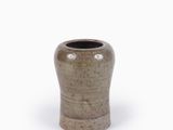 un vase marron muni d'une poignée en bois, posé sur une surface blanche