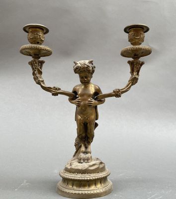 un candélabre ancien en laiton, muni de deux bougies et posé sur un socle