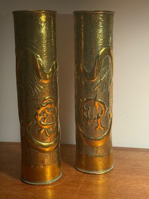 two gold vases on a wooden table with a white wall in the background