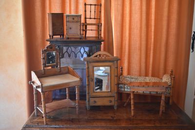 a small table with a clock and a chair in front of an orange curtain
